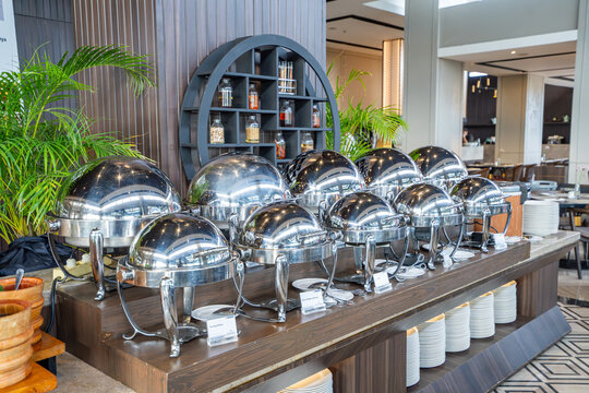 Luxury hotel buffet line with stainless chafing dishes in modern restaurant interior, showcasing premium catering service, elegant dining setup, and high end hospitality experience.
