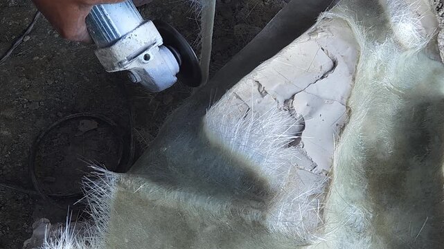 Close-up of a skilled artist using an angle grinder to cut and shape a fibre sculpture, captured in slow motion. The scene highlights precision craftsmanship, manual work, and industrial tools, India