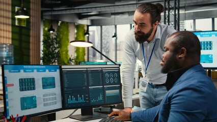 Diverse corporate team focuses on data management on computer, planning strategies for company...