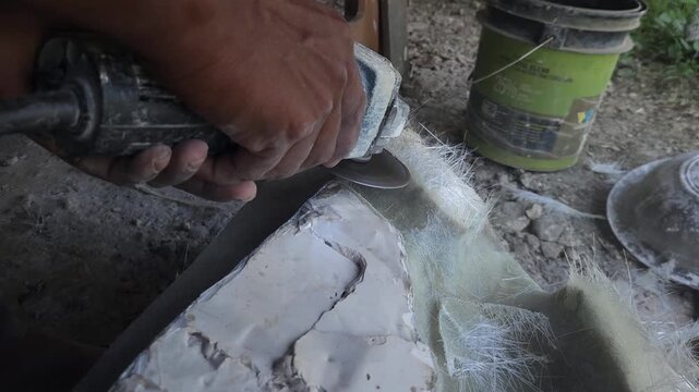 Close-up of a skilled artist using an angle grinder to cut and shape a fibre sculpture, captured in slow motion. The scene highlights precision craftsmanship, manual work, and industrial tools, India