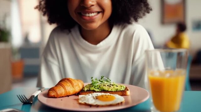 Happy smiling gen Z girl of black ethnicity with curls showing her colorful delicious and healthy breakfast with eggs, avocado and greens at camera, doing selfie for her social network page. Pastel 