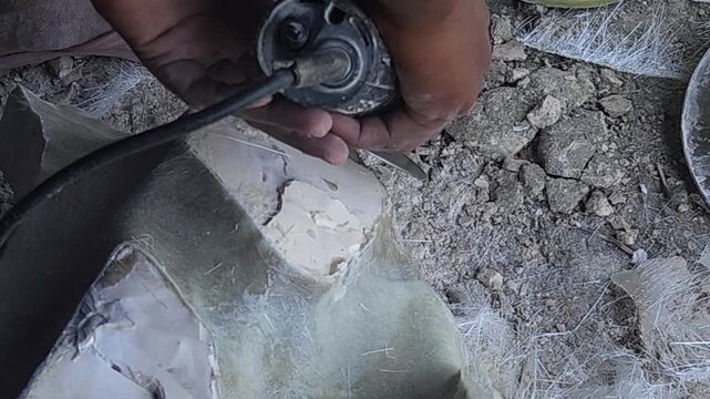 Close-up of a skilled artist using an angle grinder to cut and shape a fibre sculpture, captured in slow motion. The scene highlights precision craftsmanship, manual work, and industrial tools, India