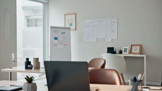 Modern office workspace with computer, chair, and desk near window with city view and blurred background of whiteboard and calendar