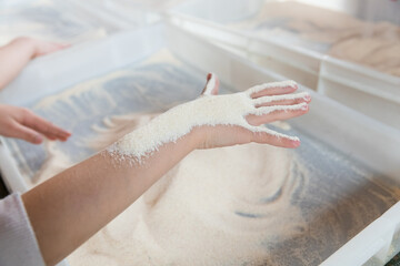 Naklejka premium Child's hands exploring semolina texture. Sensory development and motor skills therapy for kids.
