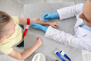 Obraz premium Doctor drawing blood sample of patient with syringe at table in clinic, top view