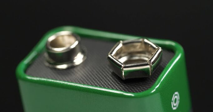 Nine-volt battery, or 9-volt battery - electric battery that supplies a nominal voltage of 9 volts. Nine-volt battery with terminals. Green 9-volt battery ready to power devices