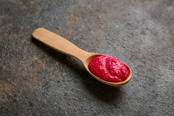 Spoon of horseradish sauce with beet on black grunge background, closeup