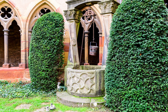 A communal well with a bucket hanging from a pulley at the Unterlinden Museum in Colmar, France.