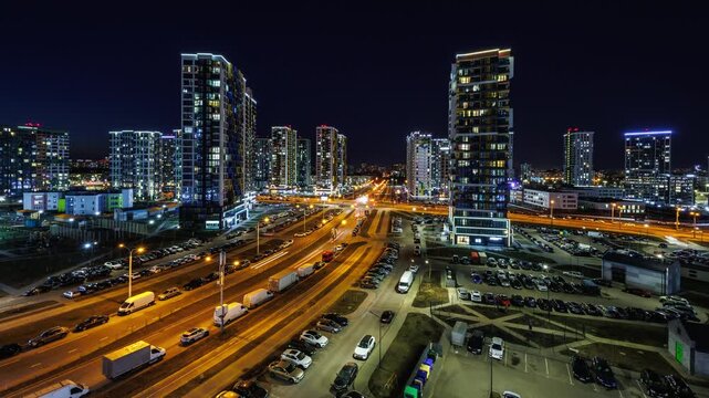 night time lapse with light in windows of multistory skyscraper buildings and avenue and lights from car headlights. life in a big city. Serenade of light