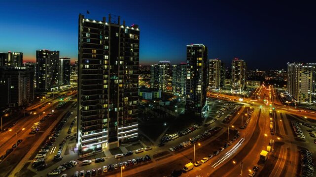night time lapse with light in windows of multistory skyscraper buildings and avenue and lights from car headlights. life in a big city. Serenade of light