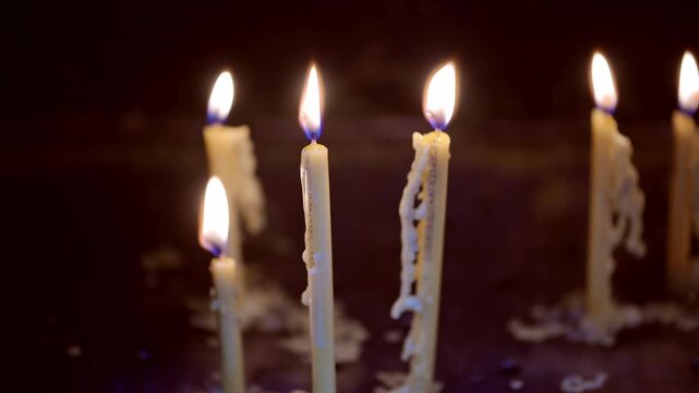 A candle burns softly, casting warm light through the gap of heavy metal doors