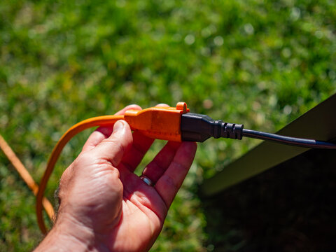 A person connects an orange outdoor extension cord