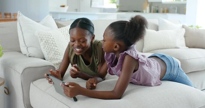 Vertical video: Older sis olive top tapping tablet, younger in purple leaning and laughing on couch