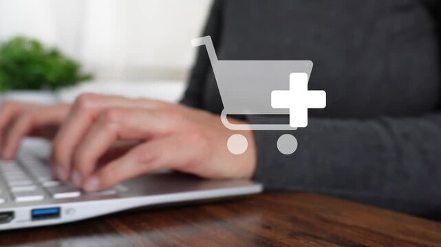 Close-up of a woman's hand working on a computer, pointing to an animated shopping icon with the "add to cart" button.