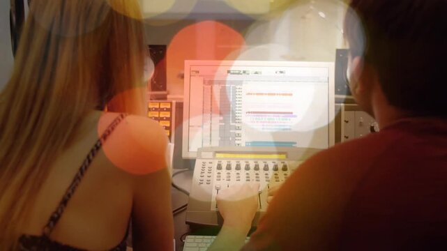 Starting session man tee and woman strappy top adjusting faders mixing at control desk with DAW