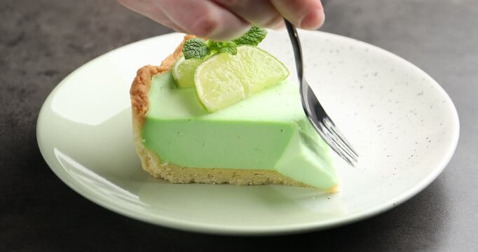 Woman eating piece of delicious lime pie at grey table, closeup