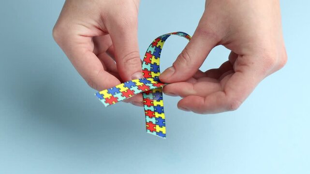 Autism. Woman with colorful ribbon on light blue background, closeup