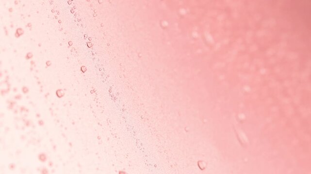 Water drops falling and draining on pink background, closeup