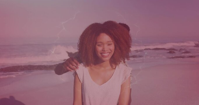 Woman posing center man coming right wrapping arms kissing neck eliciting laughter romance waves