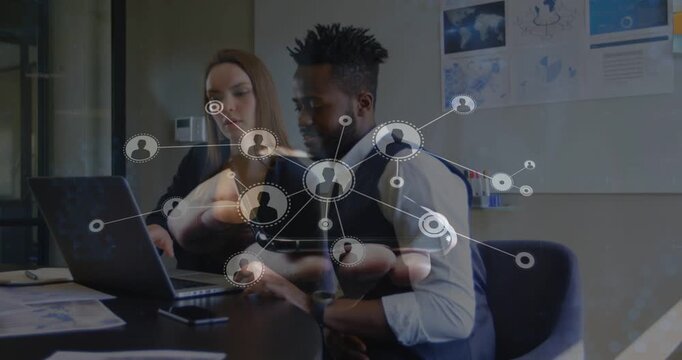 Two colleagues pointing and typing starting growing network overlay over laptop showing IT teamwork