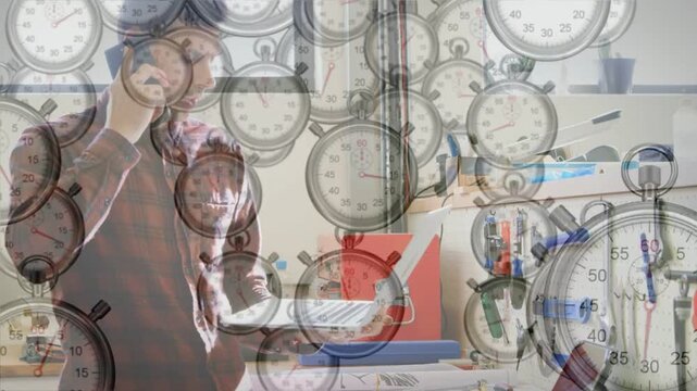 Technician raising phone and checking docs for parts in tech workshop, stopwatches overlaying scene