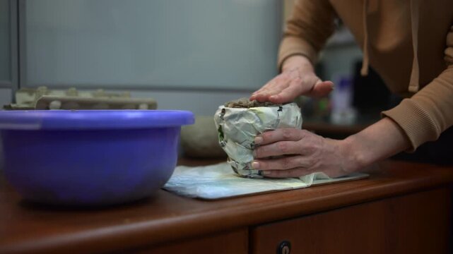 Closeup Of Hands Forming Damp Mud Layers. Studio Technique Of Pressing Moist Soil Into Paper Molds. Media