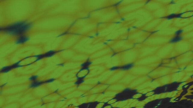 Abstract green and yellow pattern with dark irregular shapes creating a textured, fluid, and kaleidoscopic visual effect.