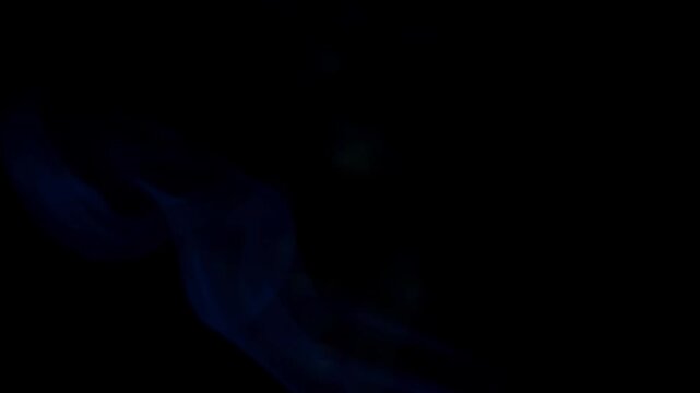 Abstract footage of flowing blue smoke drifting gracefully against a dark black background, creating a dramatic and cinematic atmospheric effect. The soft swirling vapor patterns