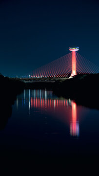 Ponte estaiada sobre o rio poti, iluminada de cor vermelha a noite.