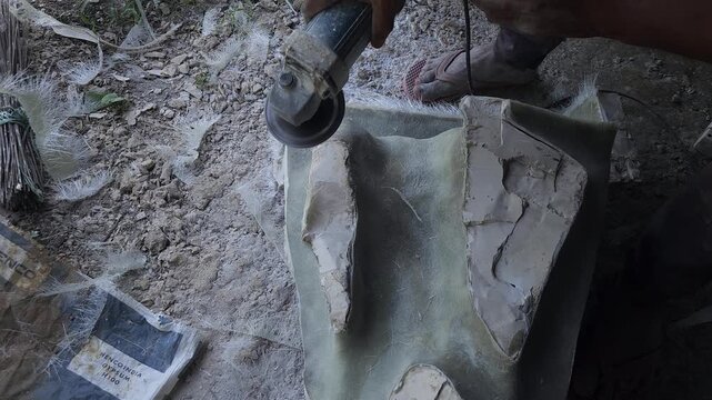 Close-up of a skilled artist shaping a fibre sculpture, detailed craftsmanship, manual labor, and creative industrial work in a workshop setting. Ideal for themes of sculpture making, manufacturing