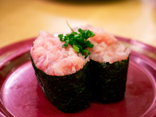 Negitoro minced fatty tuna gunkan maki sushi topped with green onion on red plate, Japanese restaurant © Tavan