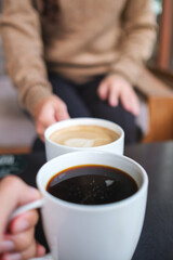 Vertical closeup image of couple people clinking coffee cups in cafe