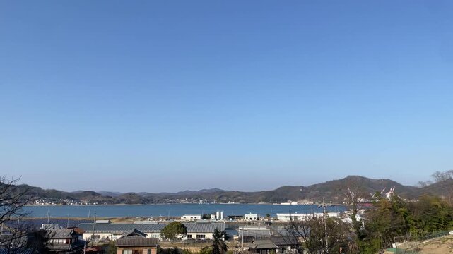 A calm coastal scene in the Seto Inland Sea, Japan. Gentle waves move quietly under soft natural light, with a peaceful island landscape in the distance. The atmosphere is still and minimal, capturing