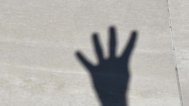 Shadow of a Hand Counting from One to Five on Concrete