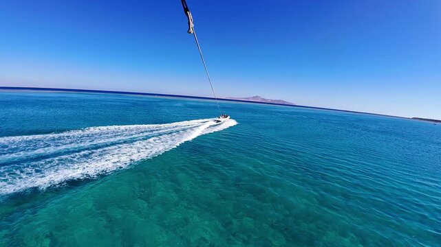 FPV parasailing over clear blue ocean speed boat wake below water sport
