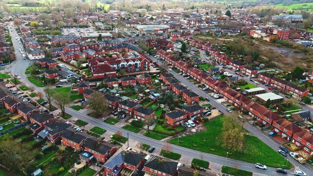 aerial drone landscape shot over Romsey, Hampshire, England Town village in spring sunset surrounded by nature trees and fields with golden warm light above. Calm quiet roads and paths below
