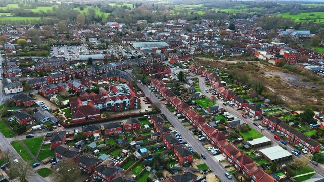 aerial drone landscape shot over Romsey, Hampshire, England Town village in spring sunset surrounded by nature trees and fields with golden warm light above. Calm quiet roads and paths below