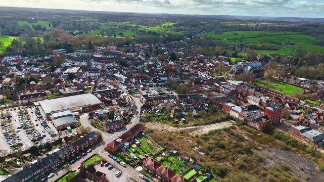 aerial drone landscape shot over Romsey, Hampshire, England Town village in spring sunset surrounded by nature trees and fields with golden warm light above. Calm quiet roads and paths below