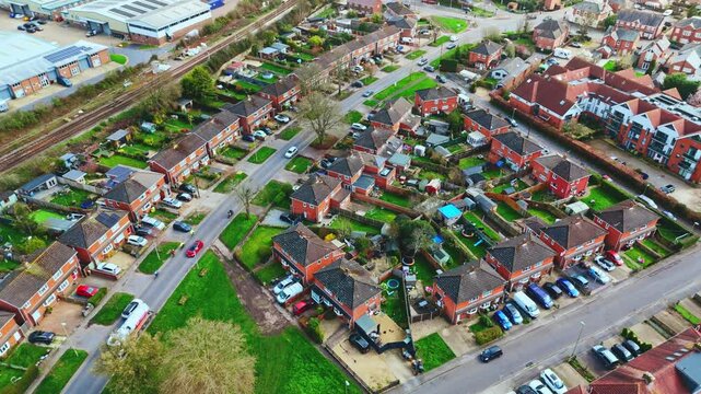 aerial drone landscape shot over Romsey, Hampshire, England Town village in spring sunset surrounded by nature trees and fields with golden warm light above. Calm quiet roads and paths below