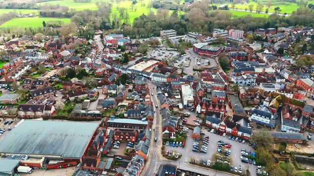 aerial drone landscape shot over Romsey, Hampshire, England Town village in spring sunset surrounded by nature trees and fields with golden warm light above. Calm quiet roads and paths below
