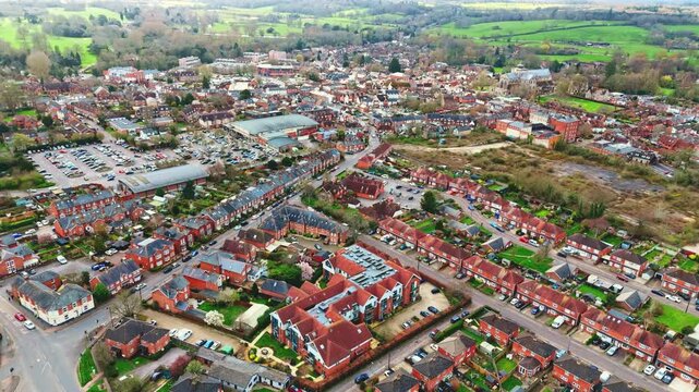aerial drone landscape shot over Romsey, Hampshire, England Town village in spring sunset surrounded by nature trees and fields with golden warm light above. Calm quiet roads and paths below