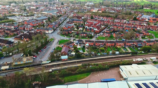 aerial drone landscape shot over Romsey, Hampshire, England Town village in spring sunset surrounded by nature trees and fields with golden warm light above. Calm quiet roads and paths below