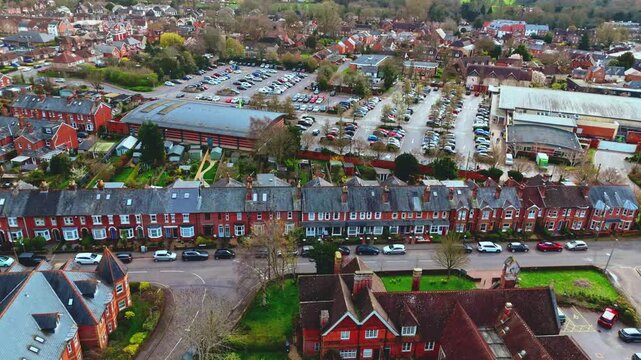aerial drone landscape shot over Romsey, Hampshire, England Town village in spring sunset surrounded by nature trees and fields with golden warm light above. Calm quiet roads and paths below