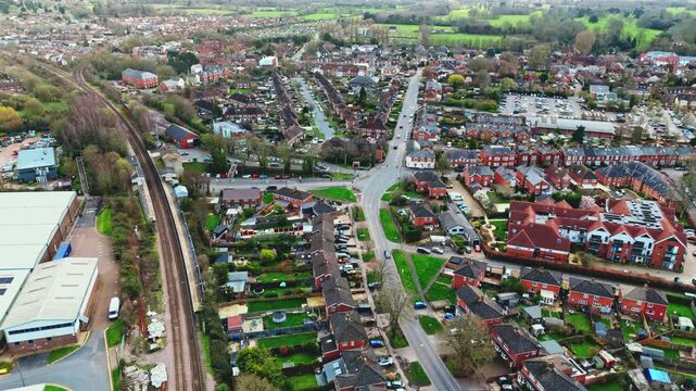 aerial drone landscape shot over Romsey, Hampshire, England Town village in spring sunset surrounded by nature trees and fields with golden warm light above. Calm quiet roads and paths below