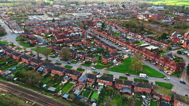 aerial drone landscape shot over Romsey, Hampshire, England Town village in spring sunset surrounded by nature trees and fields with golden warm light above. Calm quiet roads and paths below