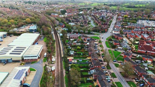 aerial drone landscape shot over Romsey, Hampshire, England Town village in spring sunset surrounded by nature trees and fields with golden warm light above. Calm quiet roads and paths below