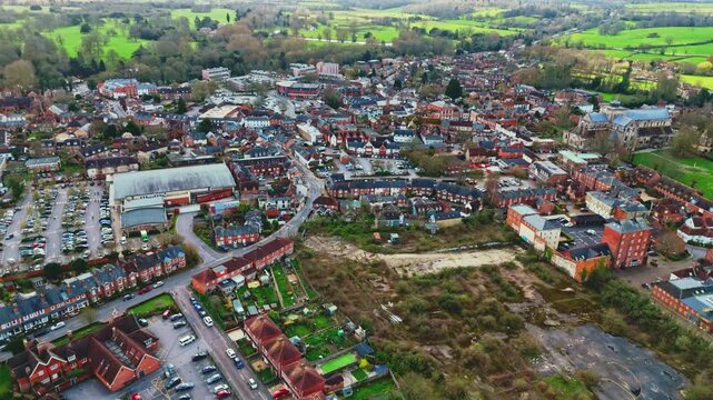 aerial drone landscape shot over Romsey, Hampshire, England Town village in spring sunset surrounded by nature trees and fields with golden warm light above. Calm quiet roads and paths below