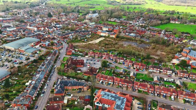 aerial drone landscape shot over Romsey, Hampshire, England Town village in spring sunset surrounded by nature trees and fields with golden warm light above. Calm quiet roads and paths below