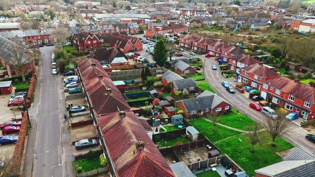 aerial drone landscape shot over Romsey, Hampshire, England Town village in spring sunset surrounded by nature trees and fields with golden warm light above. Calm quiet roads and paths below