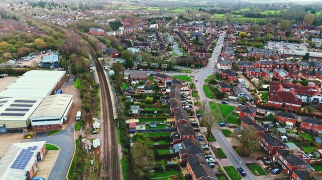 aerial drone landscape shot over Romsey, Hampshire, England Town village in spring sunset surrounded by nature trees and fields with golden warm light above. Calm quiet roads and paths below